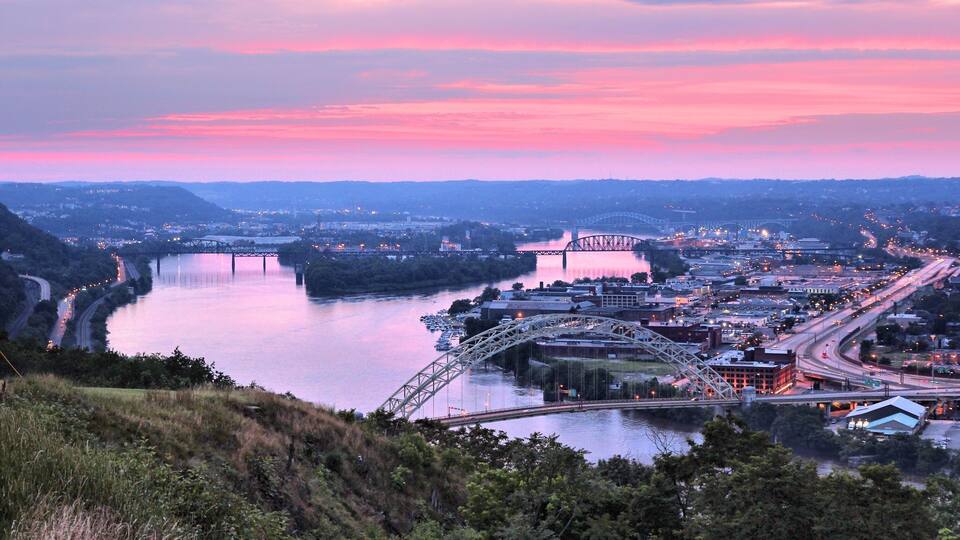 A river with a bridge, a cityscape, and a sunset.
