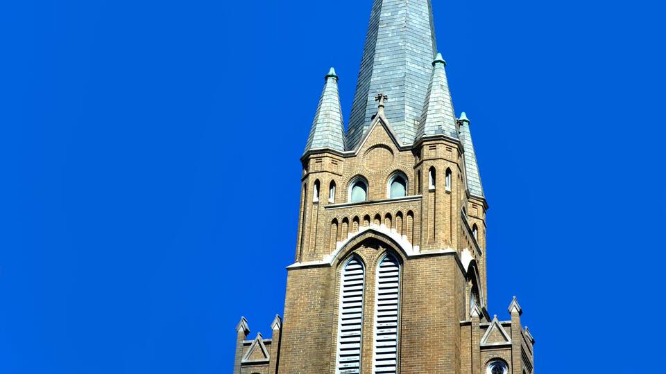 A church with a tall spire and a large arched window.