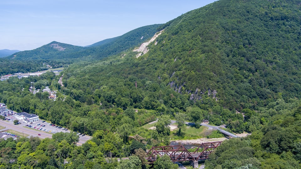 A mountainous landscape with a bridge, a parking lot, and a building.
