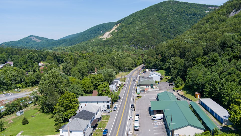 A highway cutting through a valley with buildings and greenery on either side.