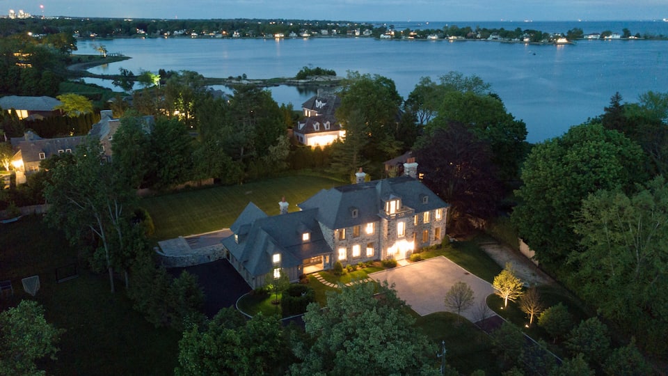 A large estate with a lake, surrounded by trees and featuring multiple illuminated buildings.
