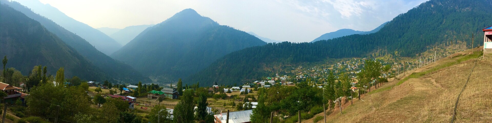 Un valle con un pequeño pueblo situado entre montañas.