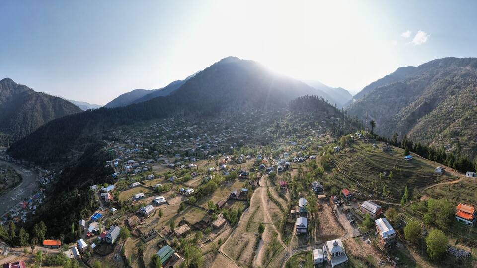 A mountainous landscape with a river, terraced fields, and scattered houses.