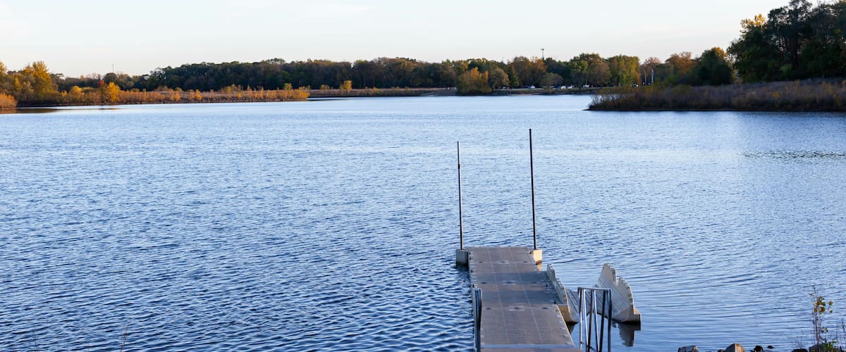 A calm lake with a wooden dock extending into the water.