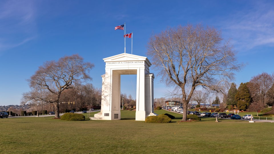 A monument with 'Children of a Common Mother' inscribed, surrounded by a grassy field and leafless trees.