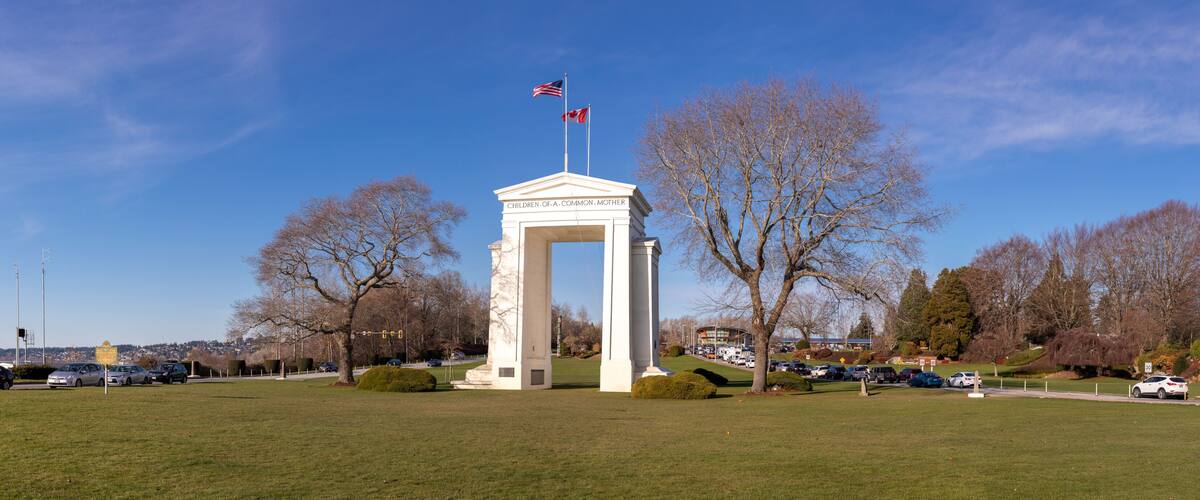A monument with 'Children of a Common Mother' inscribed, surrounded by a grassy field and leafless trees.