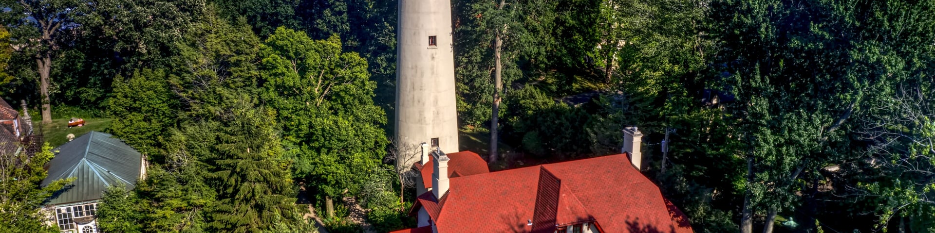 Un faro, una casa con techo rojo y una vista al mar.