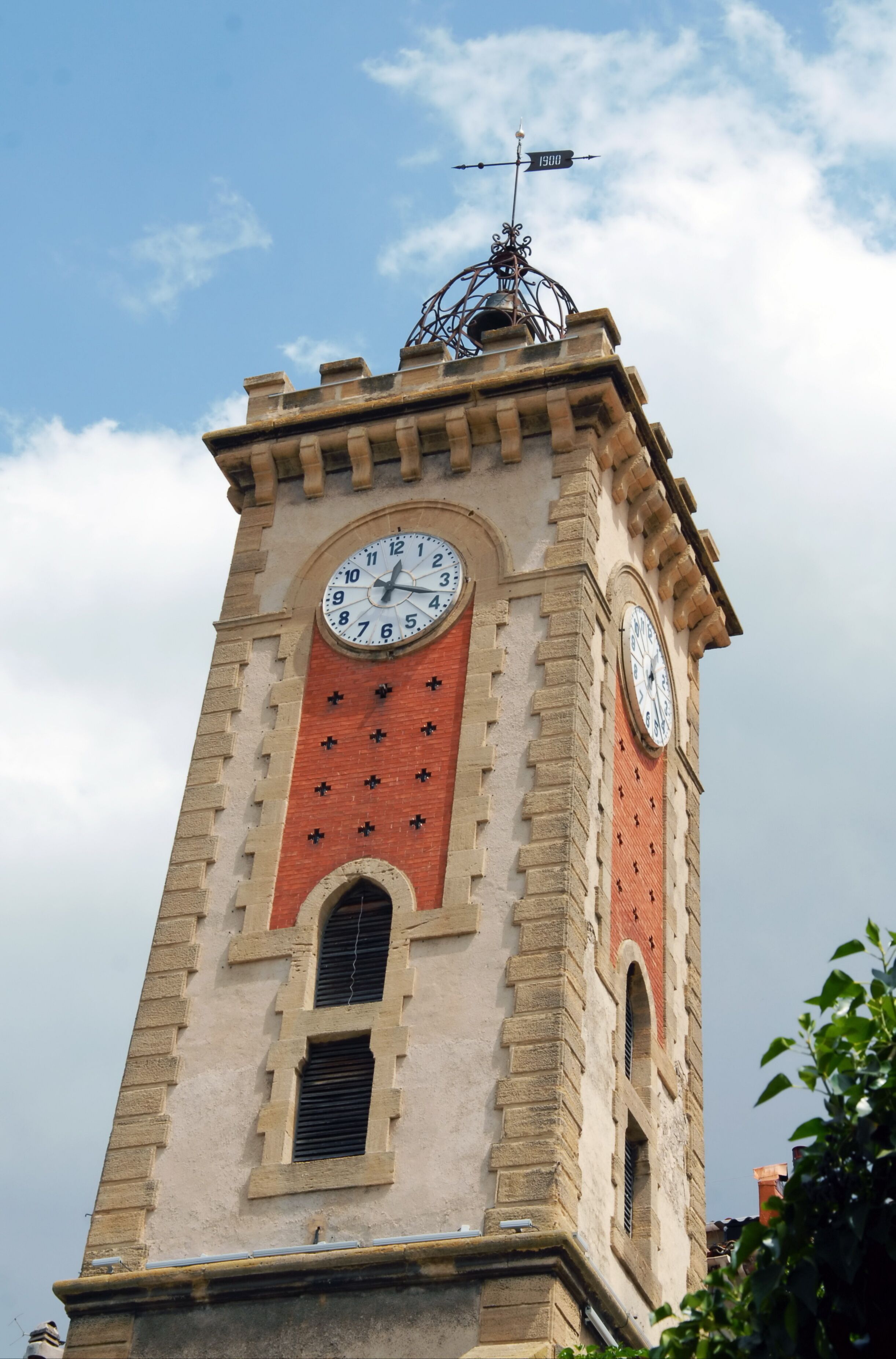 Un campanario con veleta, que presenta una esfera del reloj y una fachada de ladrillo rojo.