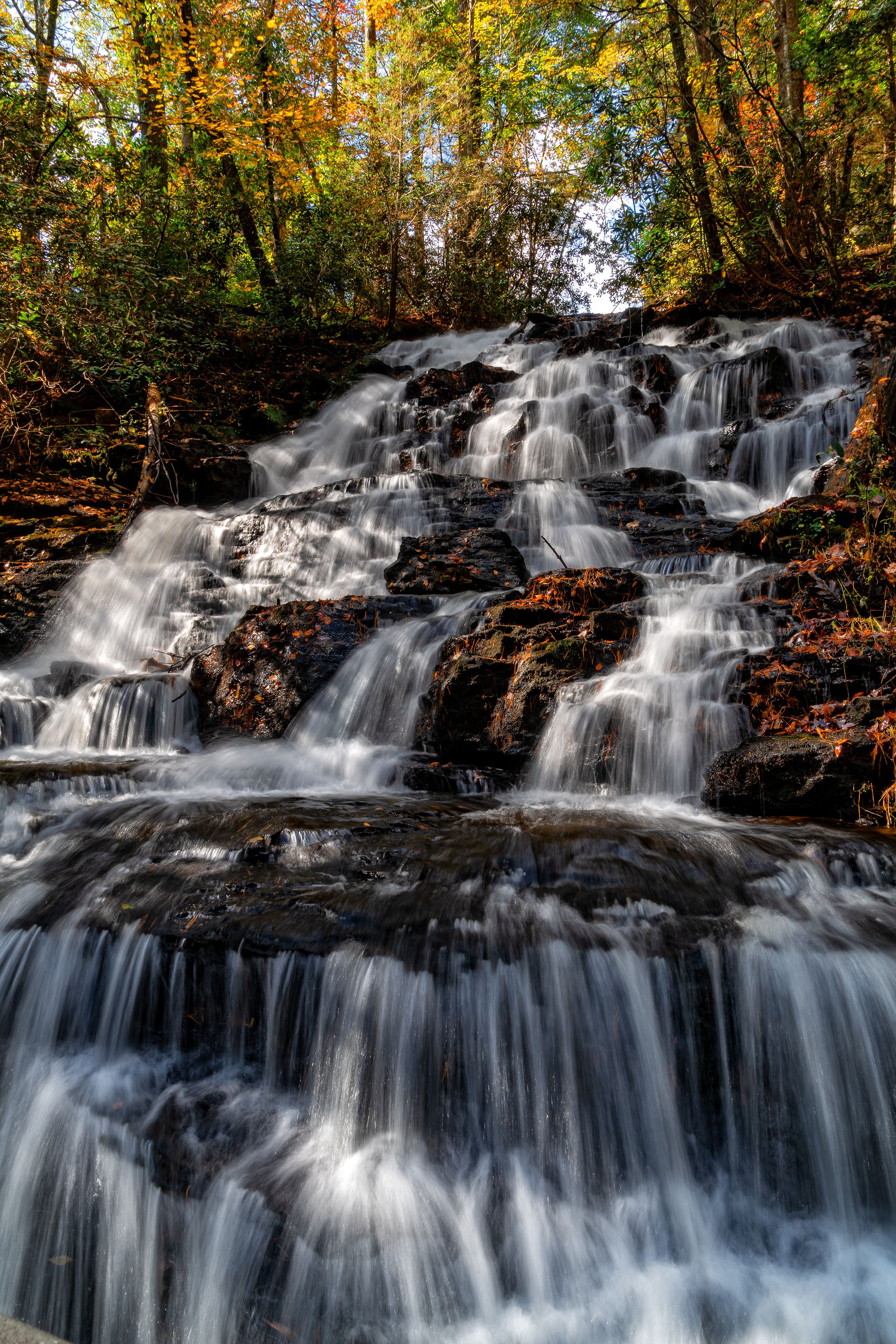 A multi-tiered waterfall surrounded by autumn foliage.