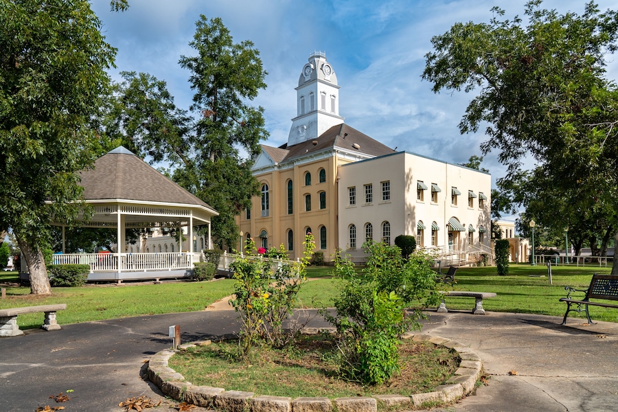 A historic building with a clock tower, a gazebo, and a well-maintained lawn.