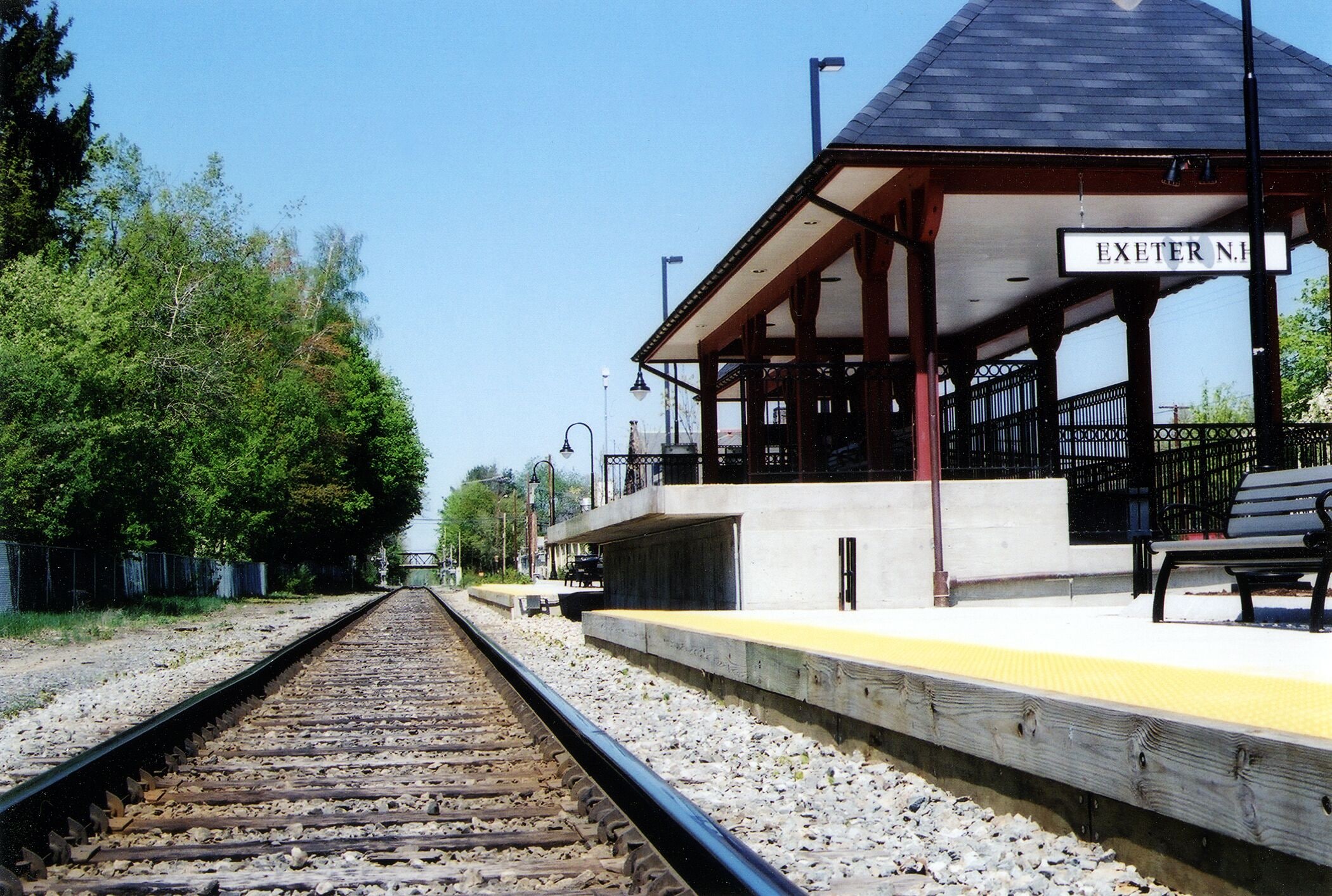 A railway station platform with a sign reading "EXETER N.H." and a bench.