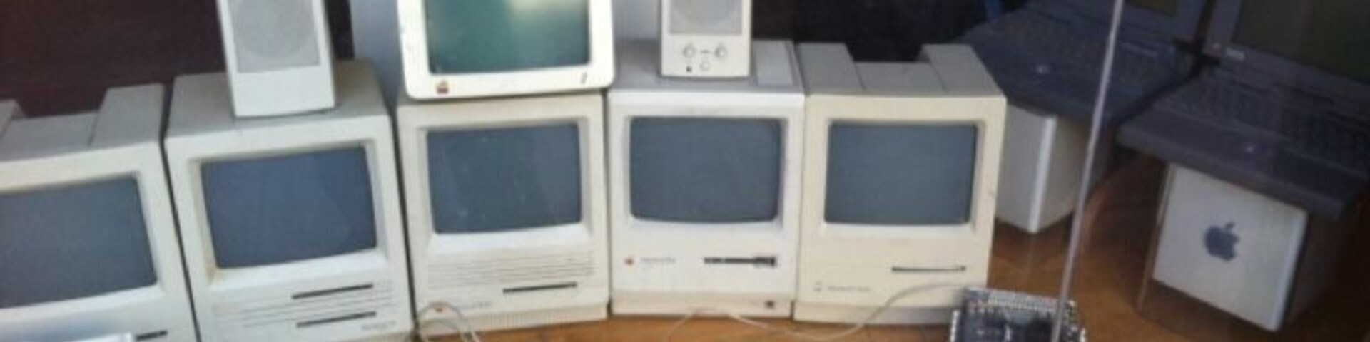 Una colección de ordenadores Macintosh antiguos y sus periféricos expuestos.