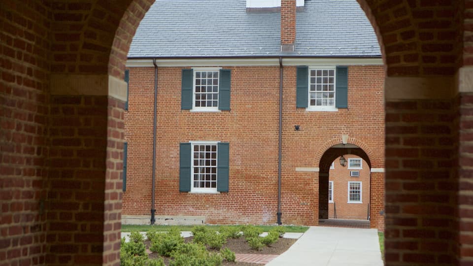 A brick building with green shutters and a central arched entrance.