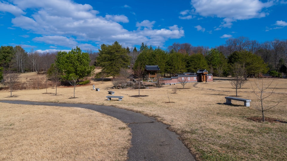 A park with a paved path, benches, and a traditional Korean pavilion.