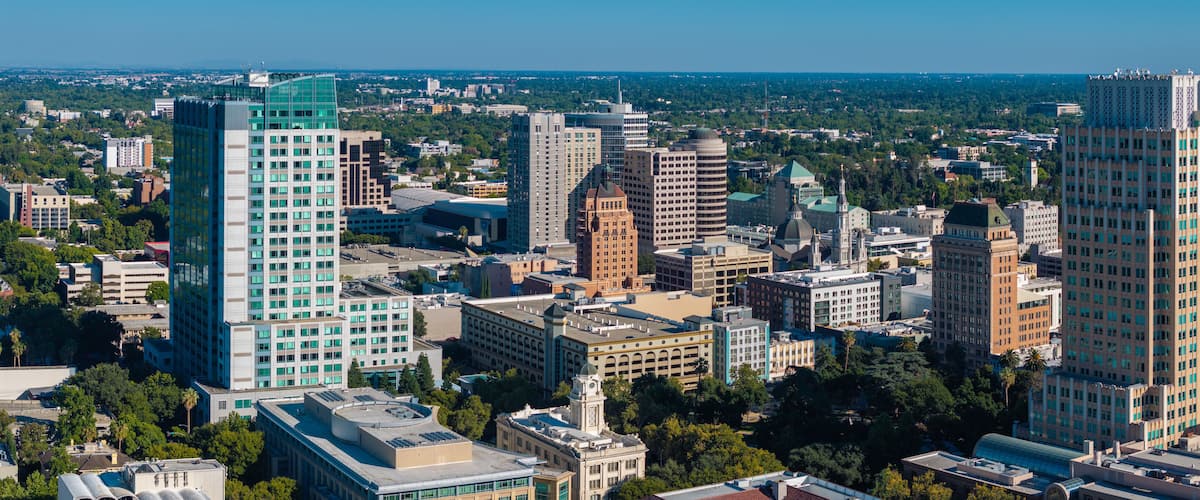 A cityscape with modern high-rise buildings, historic architecture, and a mix of greenery.