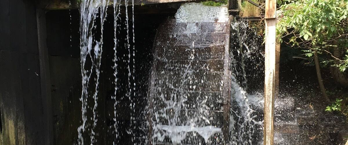 A wooden structure with a water feature, surrounded by greenery.