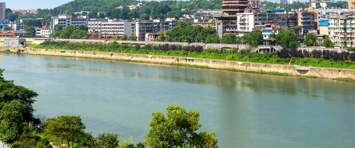A river with a traditional pagoda and modern buildings in the background.