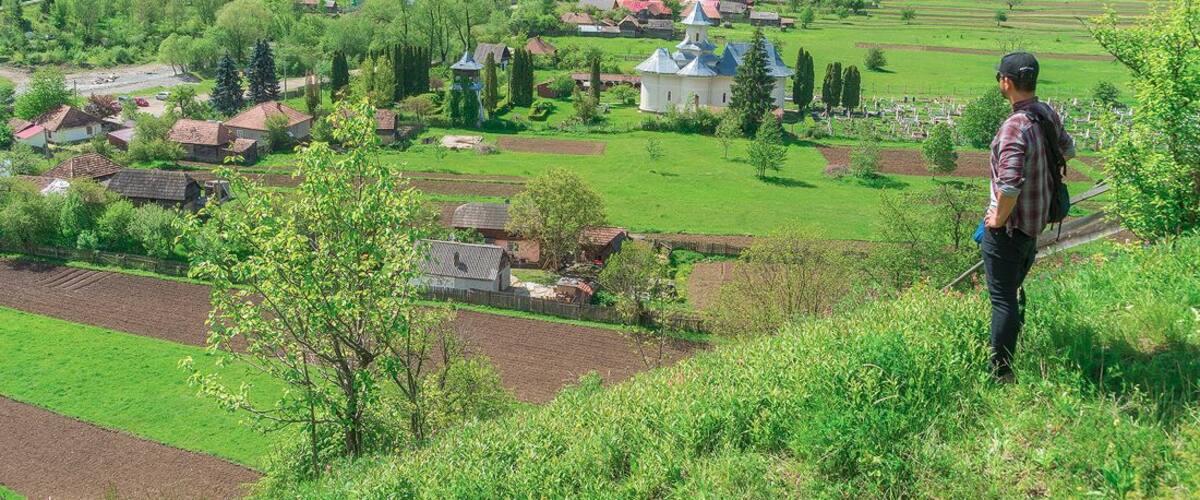 A rural landscape with a village, green fields, and a church.