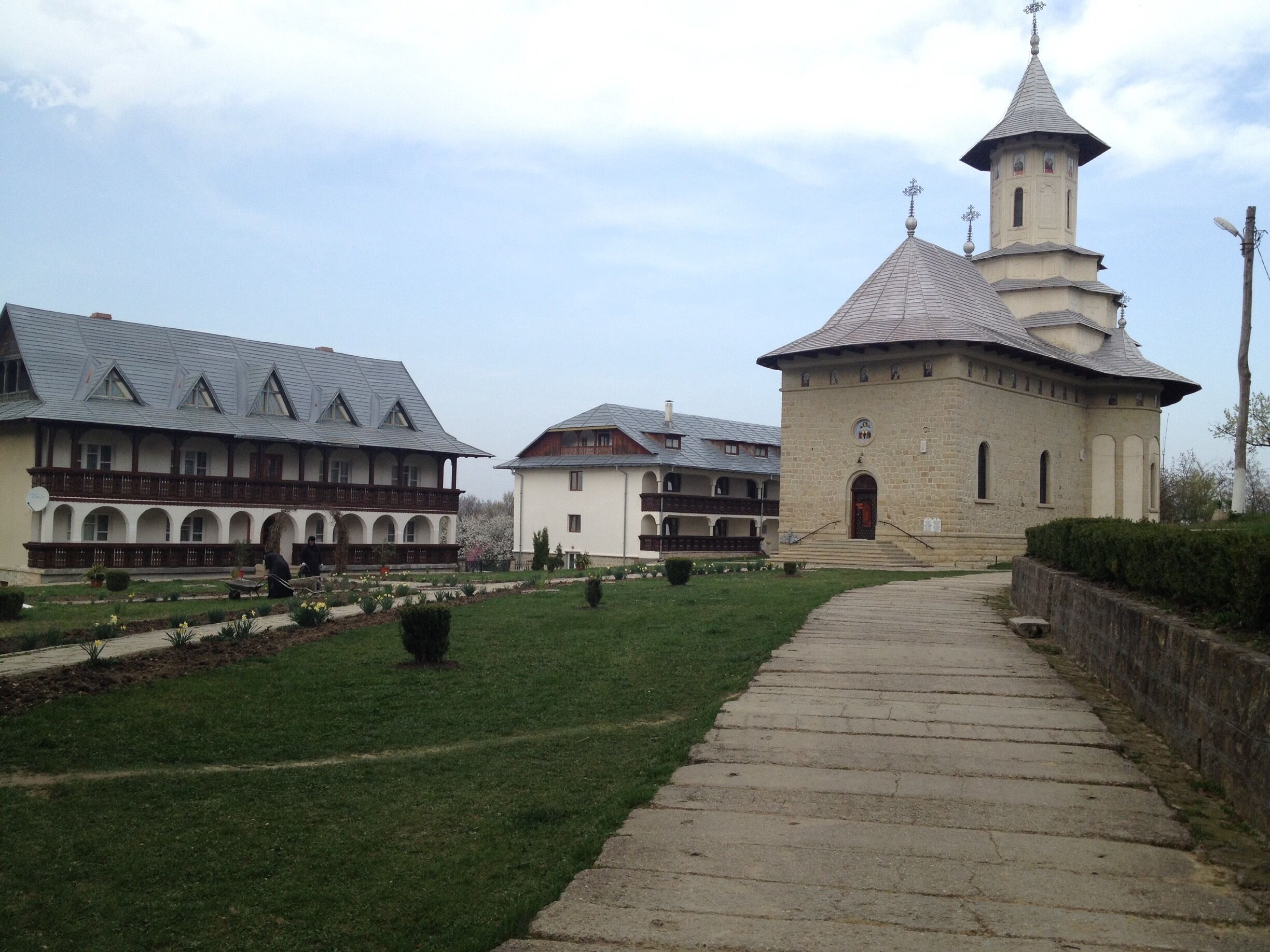 A courtyard with a pathway leading to a church with a tower.