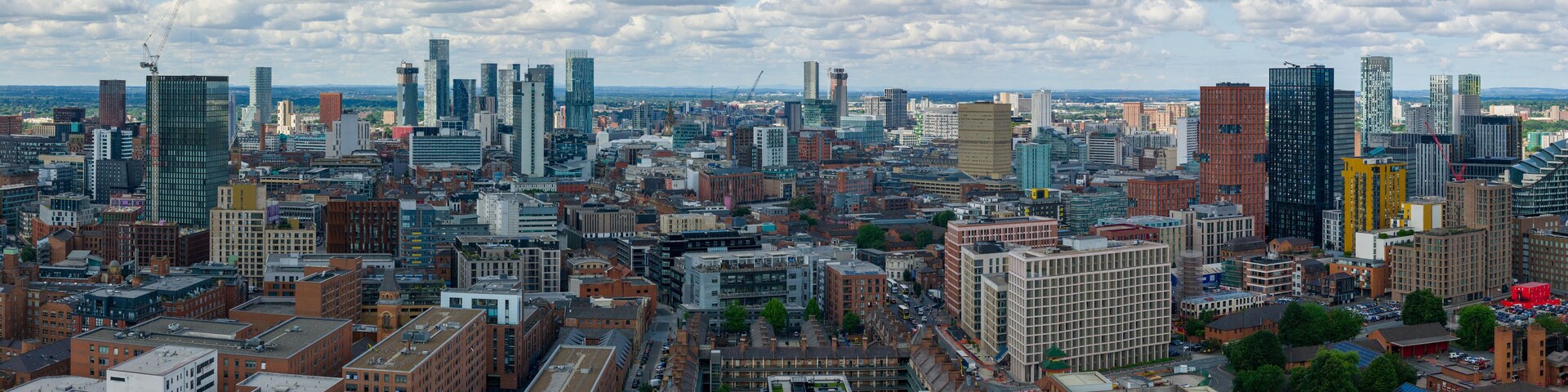 Aerial view of Manchester’s skyline with clustered tall modern towers photographed over Ancoats area.