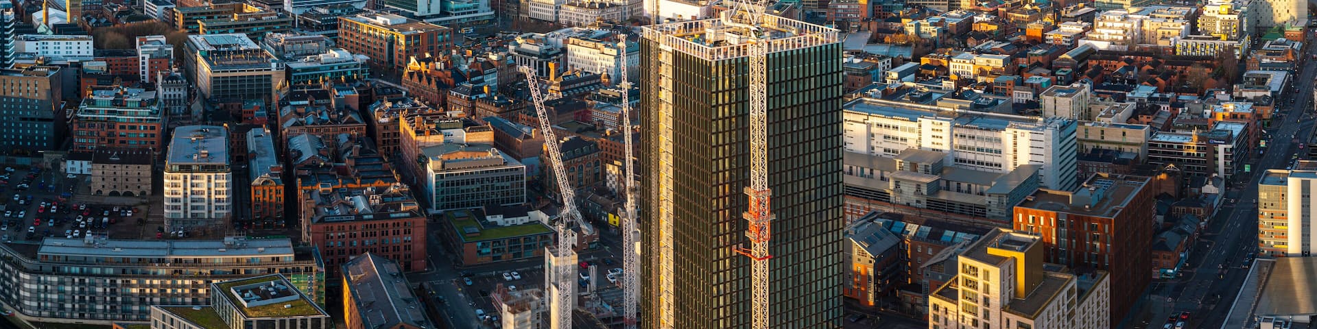 A cityscape with a prominent skyscraper, numerous buildings, and a construction crane.