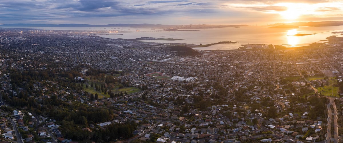 A cityscape with a large body of water in the background and a sunset.
