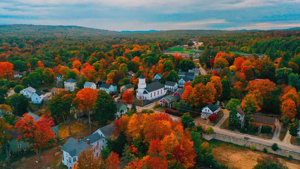 A village with houses surrounded by autumn-colored trees.
