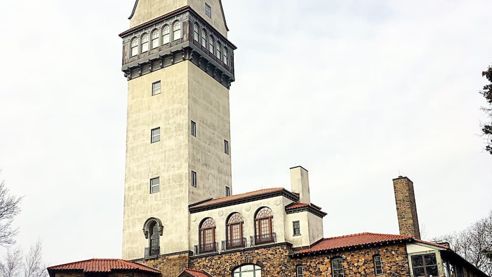 A historic building with a tall tower, stone walls, and a red-tiled roof.