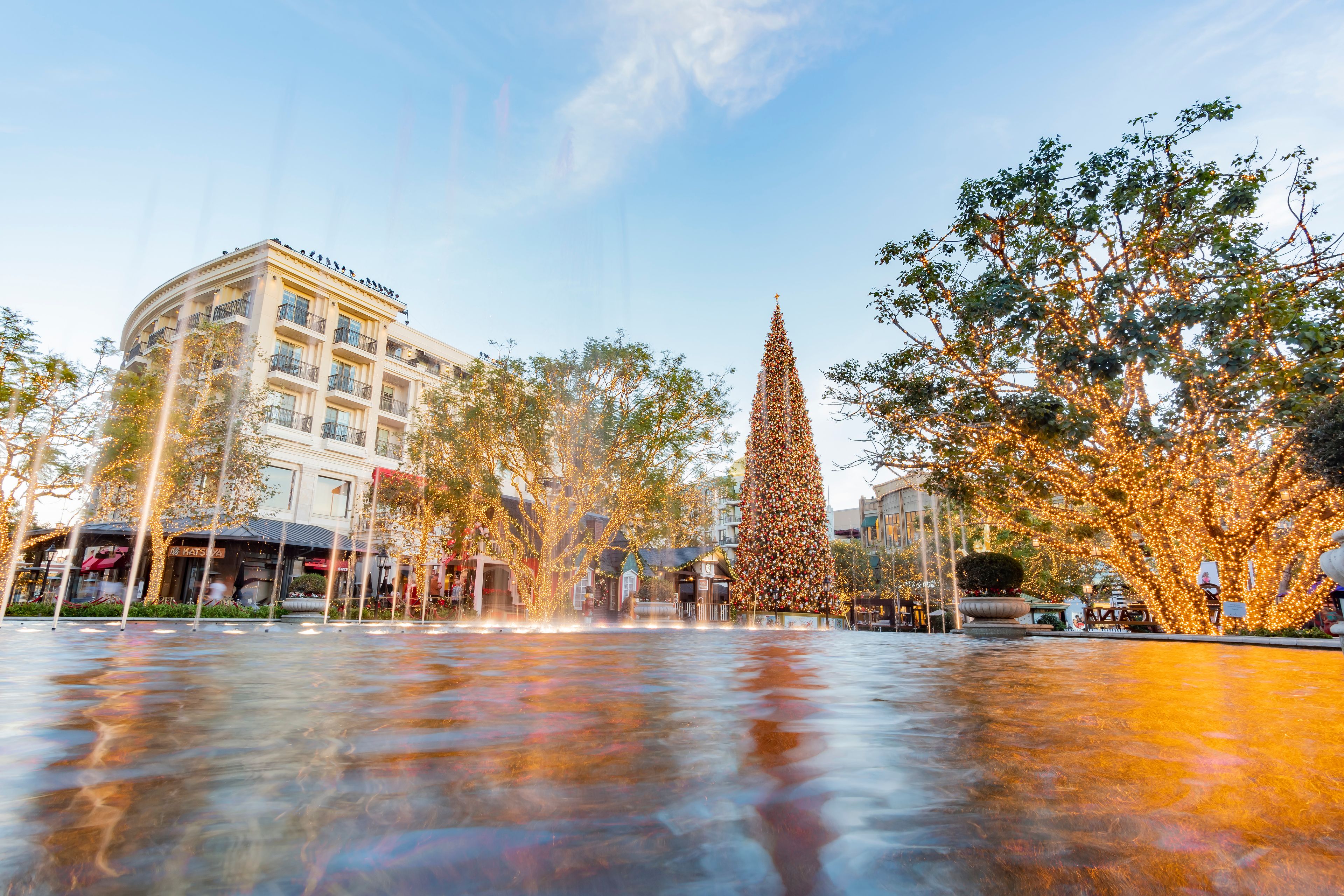 Una plaza con un gran árbol de Navidad, una fuente y edificios con balcones.