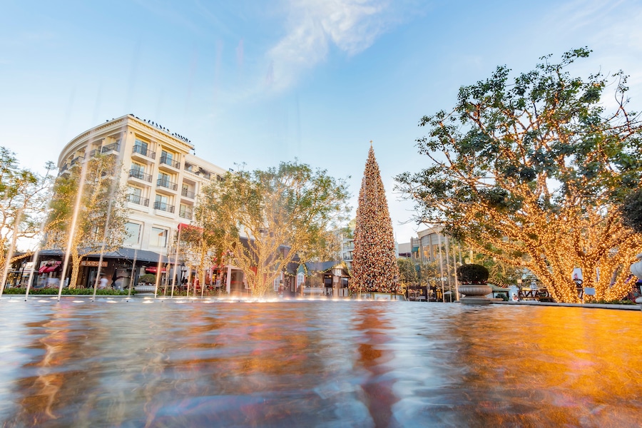 A plaza with a large Christmas tree, a fountain, and buildings with balconies.