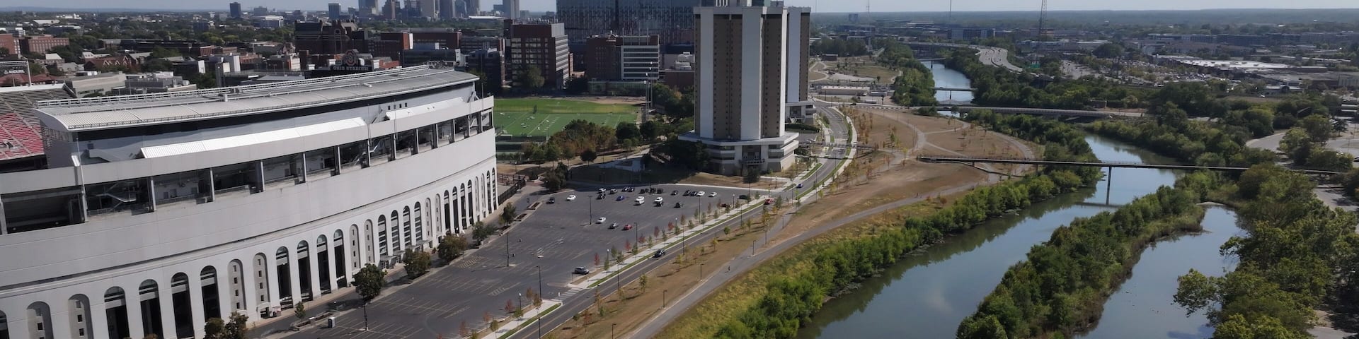 Aerial view of the Olentangy River winding past Ohio Stadium, reflecting the clear sky, alongside the bustling city skyline, Columbus, Ohio, United States.