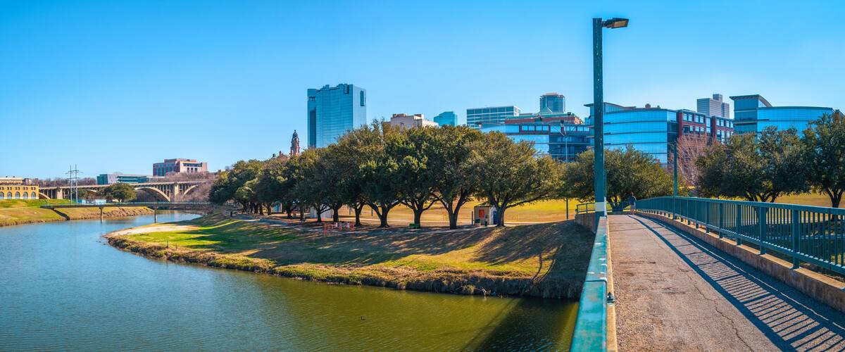 Fort Worth panoramic city skyline, buildings, and walking trails over the Trinity River Bridge, a cityscape with natural open space in Texas