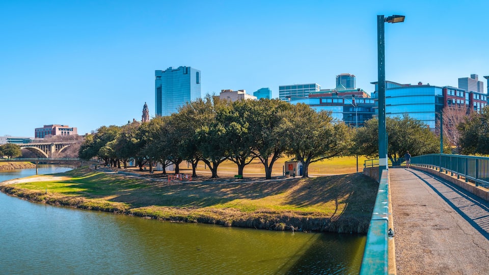Fort Worth panoramic city skyline, buildings, and walking trails over the Trinity River Bridge, a cityscape with natural open space in Texas