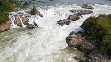 A river with multiple waterfalls surrounded by dense greenery.