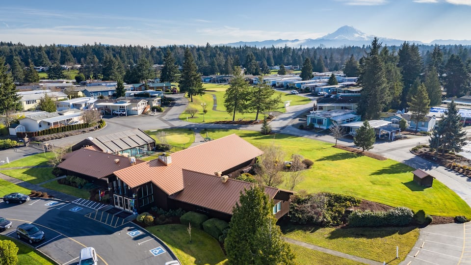 A residential area with RVs, a large building with a red roof, and a mountain in the background.