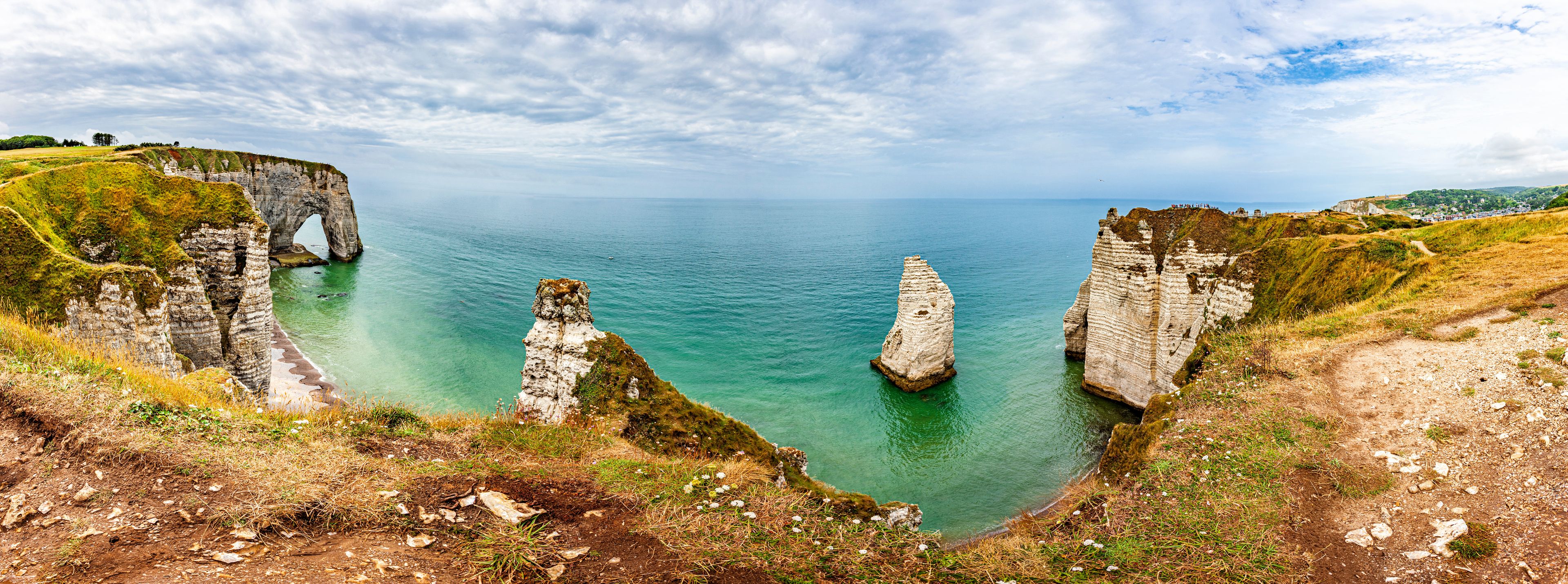 A coastal landscape with prominent chalk cliffs and a clear blue sea.