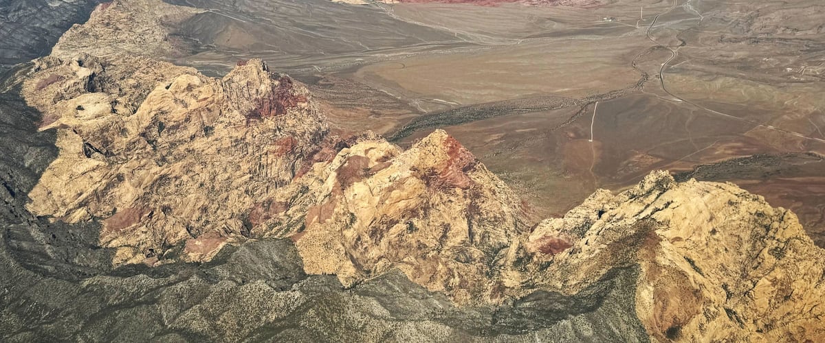 A rugged mountainous landscape with distinct geological formations and a river running through the valley.