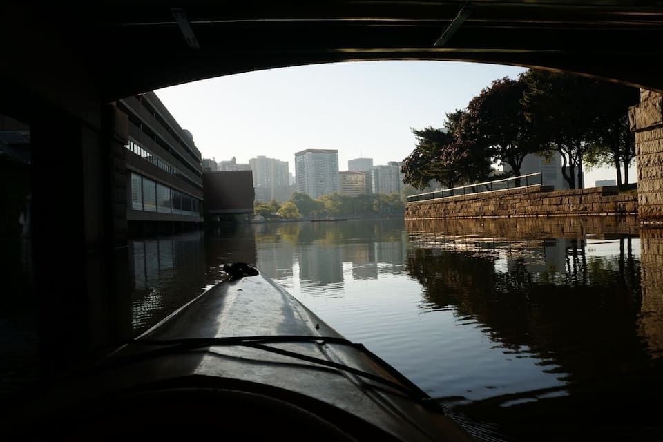 A river with a bridge, buildings, and trees in the background.