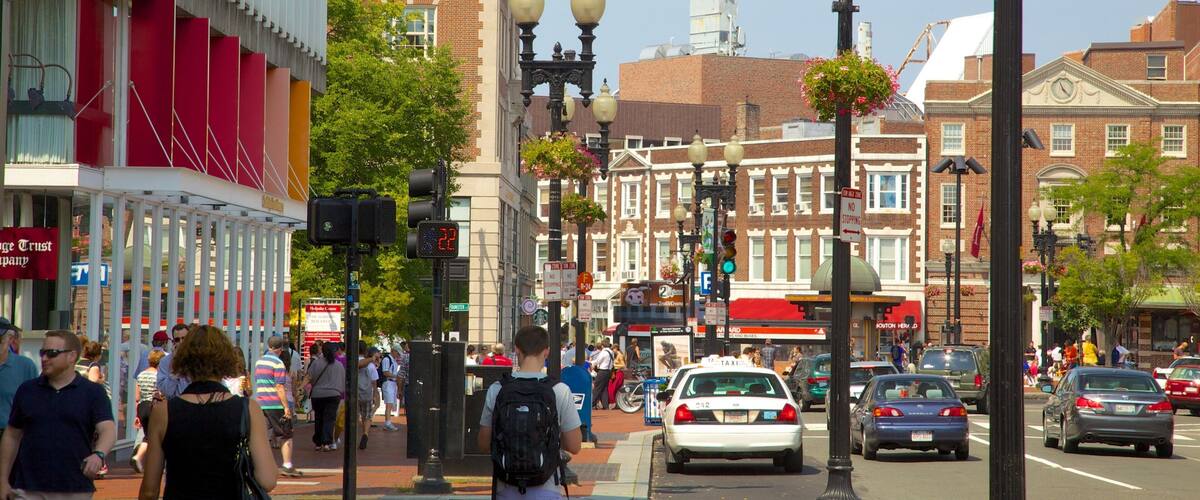 A busy urban street with pedestrians, cars, and historic buildings.