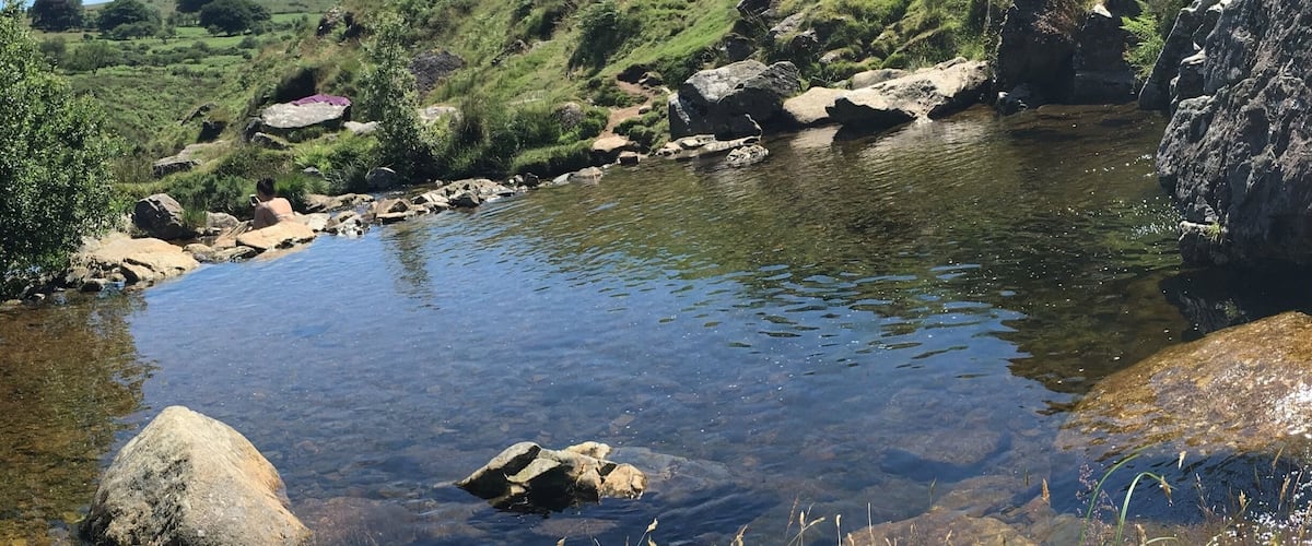 A clear stream surrounded by rocks and green grass.