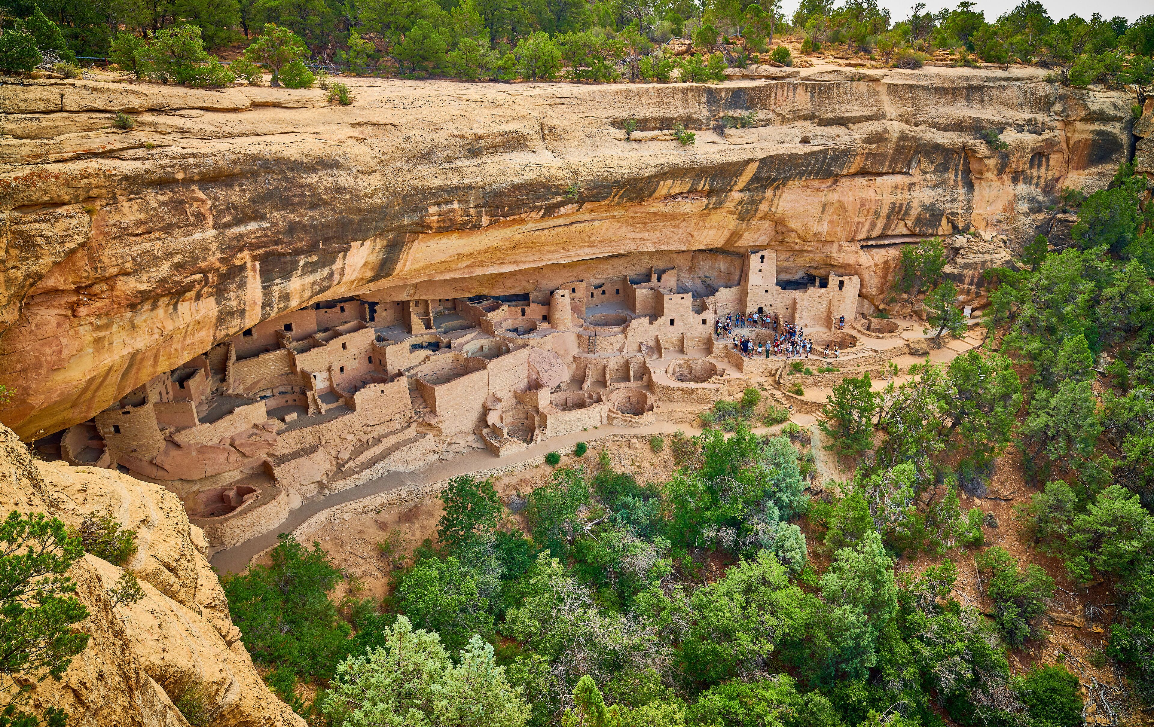 A cliffside ruin with ancient structures and dense forest.
