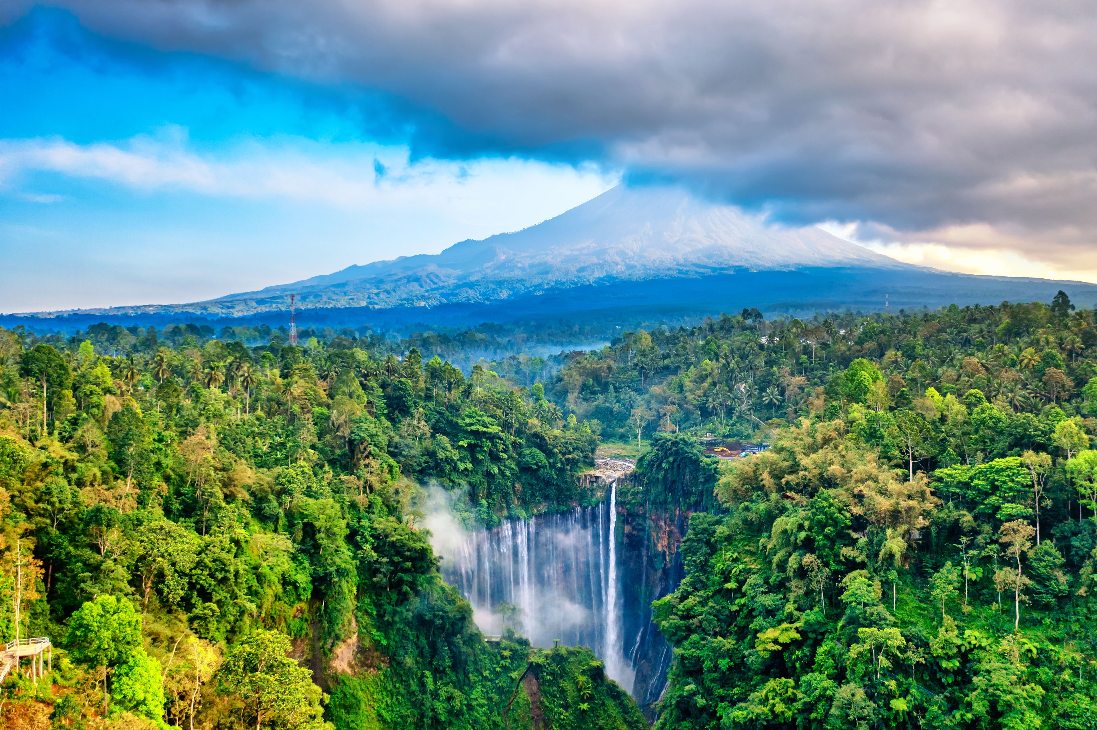 Aerial drone shot of Tumpak Sewu Waterfall and Semeru mountain at sunrise, East Java, Indonesia.