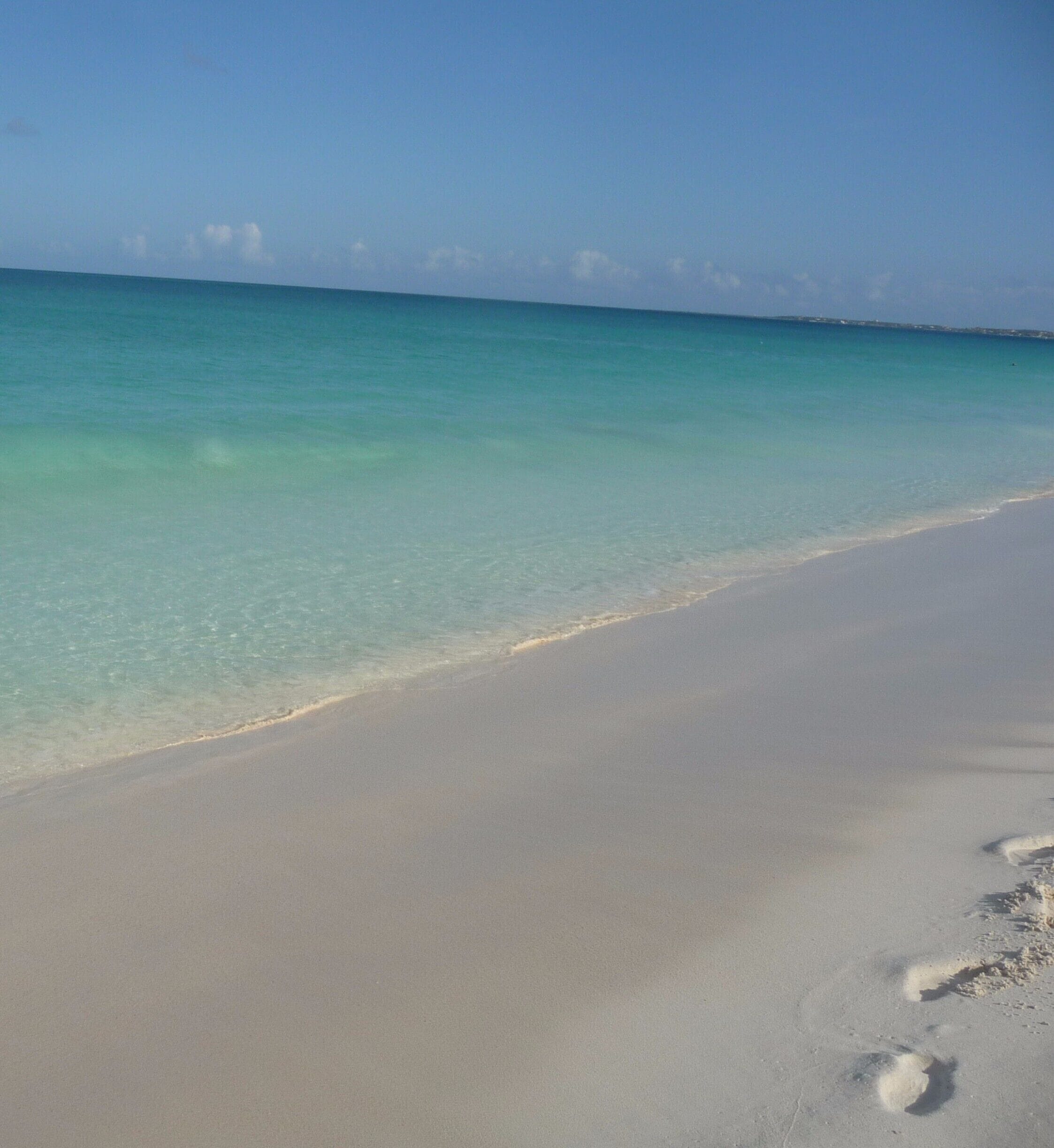 A beach with clear turquoise water and a sandy shore.