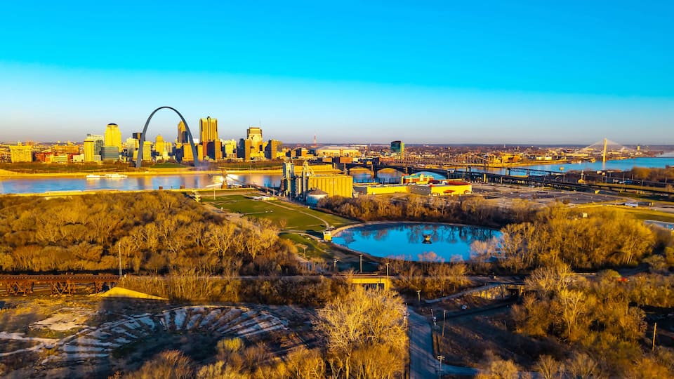 A city skyline with a river, bridges, and a large circular structure.
