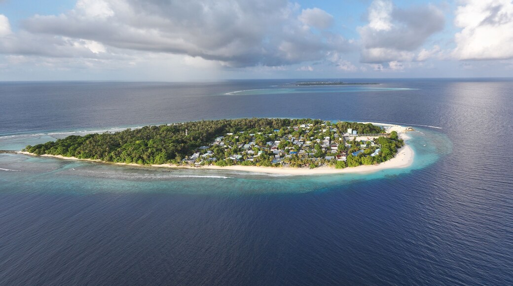 Aerial view of an island lush with green vegetation, white sandy beaches, and clusters of buildings surrounded by the deep blue sea, Maalhos, Baa Atoll, Maldives.