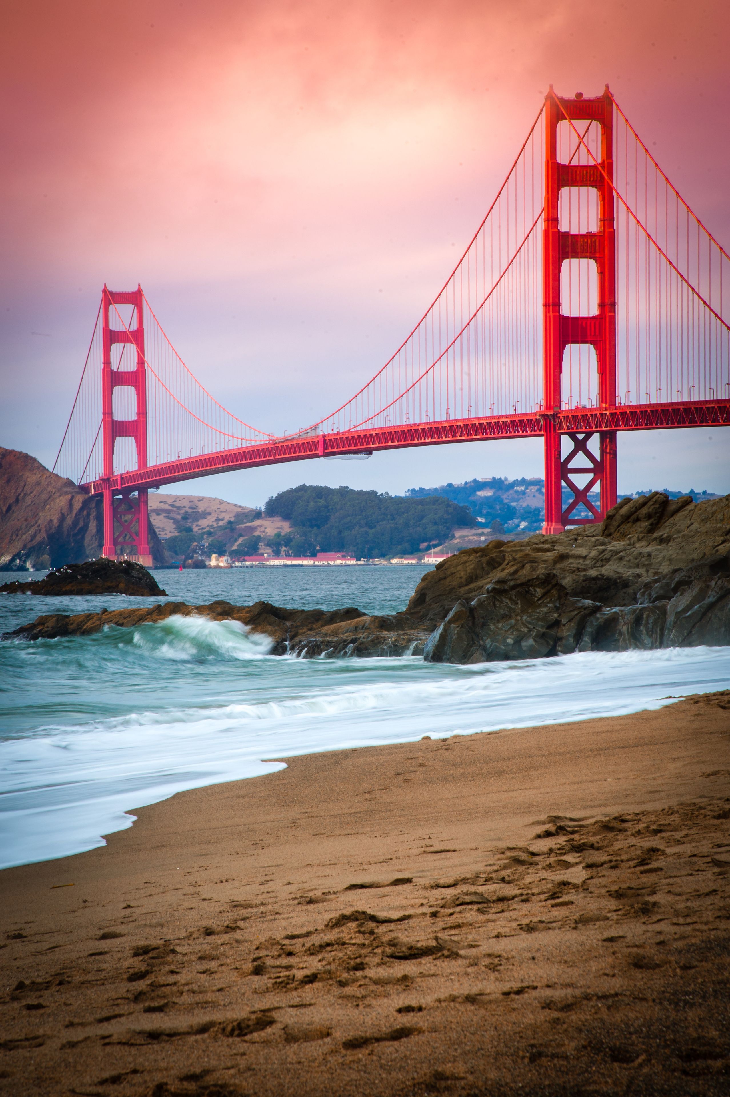 El Puente Golden Gate con una playa en primer plano y colinas al fondo.