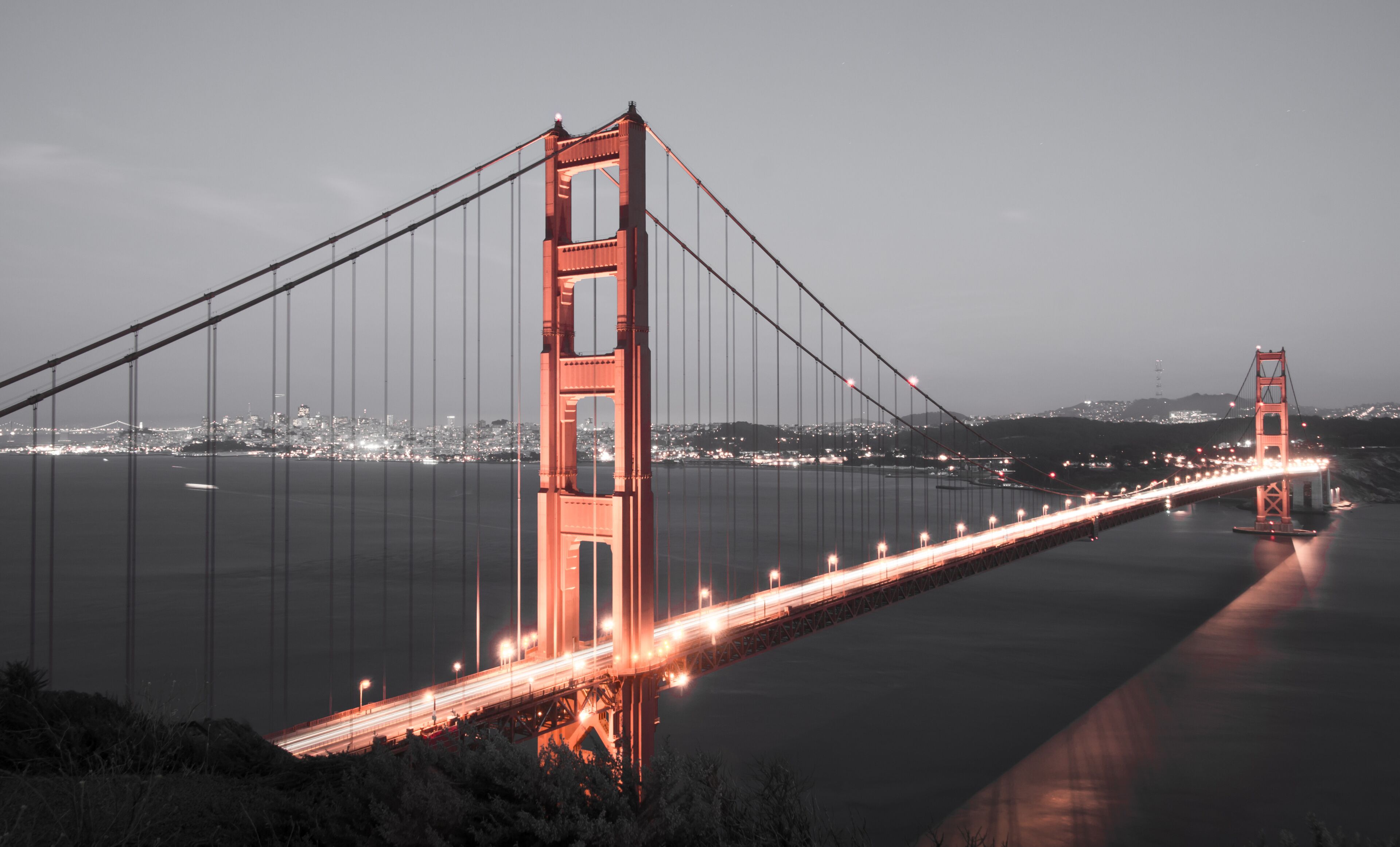 The Golden Gate Bridge at night with city lights in the background.
