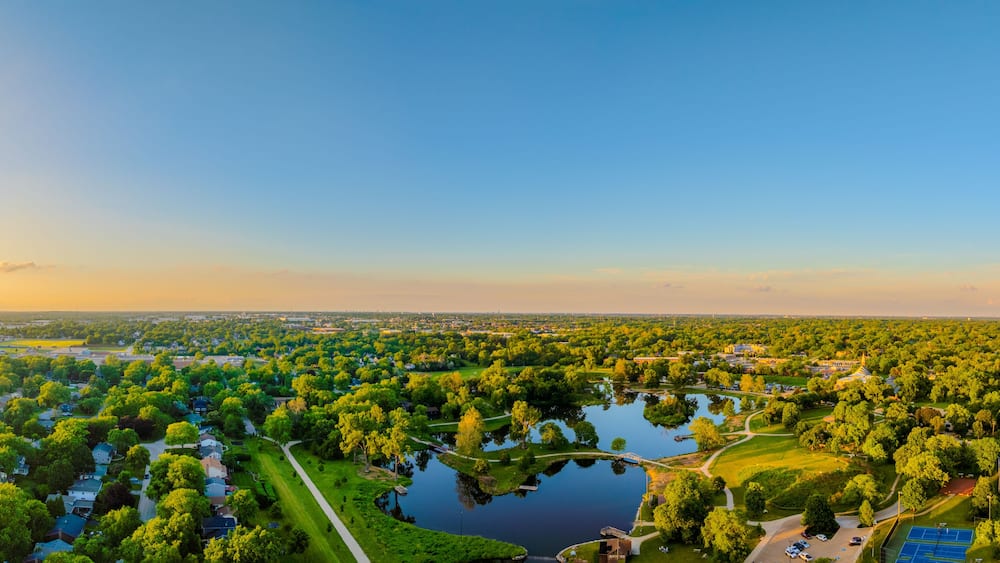 A large park with a lake, surrounded by residential areas and a distant city skyline.
