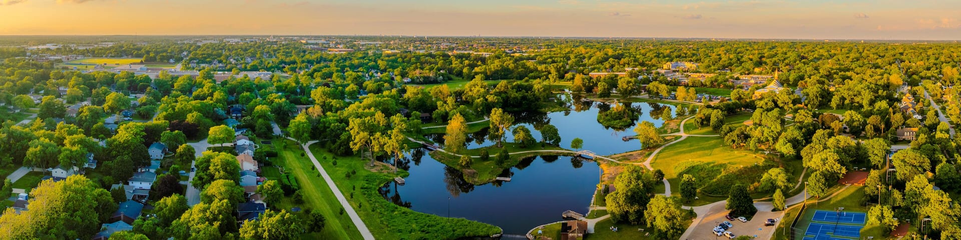 A large park with a lake, surrounded by residential areas and a distant city skyline.