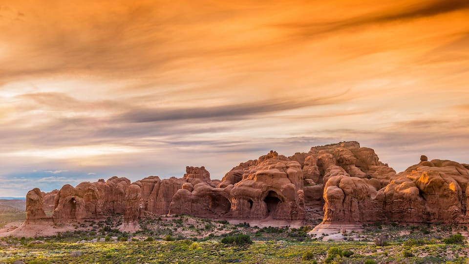 A desert landscape with prominent rock formations and sparse vegetation.